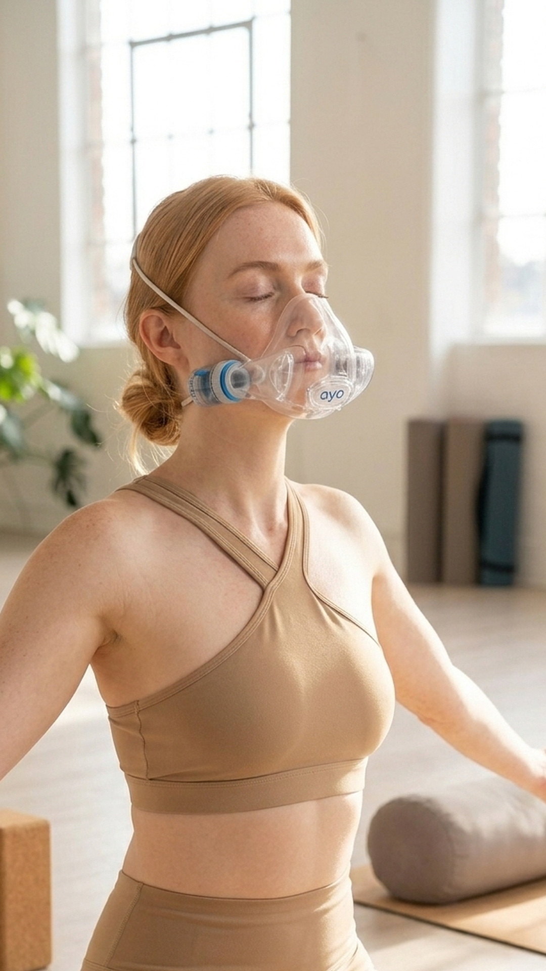 A woman in a yoga studio wearing the AYO BT breathing trainer